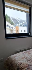 Un dormitorio con una ventana con vista a un edificio. en Apartman BJELA, en Bjelašnica