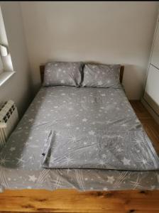Bett mit grauer Bettdecke in einem Zimmer in der Unterkunft Apartman Ristic in Požarevac