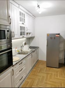 eine Küche mit weißen Schränken und einem Kühlschrank aus Edelstahl in der Unterkunft Apartman Ristic in Požarevac