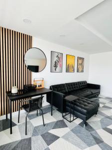 ein Wohnzimmer mit einem schwarzen Ledersofa und einem Spiegel in der Unterkunft Appartement design d’architecte in Massy