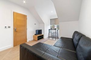 ein Wohnzimmer mit einem schwarzen Sofa und einem TV in der Unterkunft Wonderful Stay 2 Bedrooms Flat in Leicester