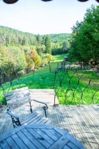 une terrasse avec une table et des bancs et une vue sur un parc dans l'établissement La Tiny House de la Bergerie, à Lierneux