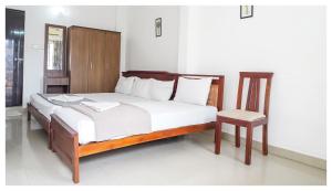 - une chambre avec un grand lit et une chaise dans l'établissement Kay Kay Residency, à Cochin