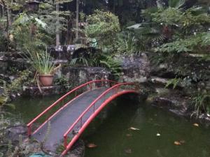 un puente rojo sobre un estanque en un jardín en COZY Inn Free Shuttle service en Nikko