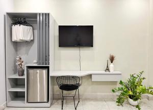 a white room with a chair and a tv on the wall at MIDMOST Boutique Hostel in Can Tho