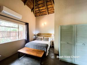a bedroom with a bed and a table and a window at 24 Degrees South Country Estate in Hoedspruit