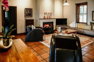 a living room with leather chairs and a fireplace at Die Stal at Antioch in Franschhoek