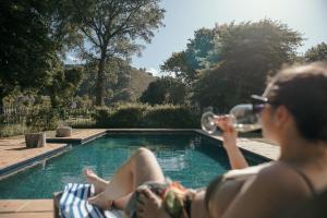a woman drinking wine next to a swimming pool at Die Stal at Antioch in Franschhoek