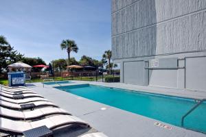 a swimming pool with lounge chairs next to a building at Willow Bay Resort in Myrtle Beach