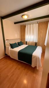 a bedroom with a large white bed with green pillows at Camping Las Palmeras in Crevillente