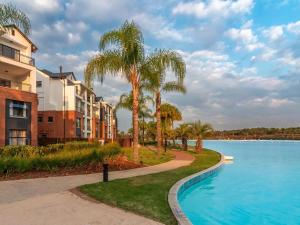 a swimming pool with palm trees next to a building at The Blyde - Posh Living in Pretoria