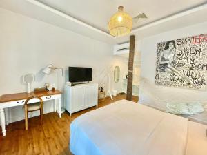 Dormitorio con cama, escritorio y TV en Green Gallery Beach Boutique Hotel, en Hua Hin