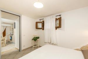 a bedroom with a white bed and a mirror at GRECALE a pochi passi dal mare in Santa Maria Navarrese