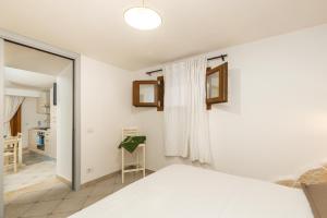 Schlafzimmer mit einem weißen Bett und einem Spiegel in der Unterkunft GRECALE a pochi passi dal mare in Santa Maria Navarrese