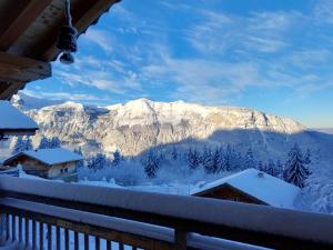 uma vista para uma montanha coberta de neve a partir de uma varanda em Chambre d'hôte dans chalet près des pistes et aux départs de randonnées em Les Carroz d'Arâches