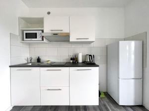 a kitchen with white cabinets and a refrigerator at Studios im Haus Deutsch Krone I home2share in Bad Rothenfelde