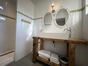 a bathroom with a sink and two mirrors on the wall at Babolène Shabby Suite in Villefranche-de-Rouergue
