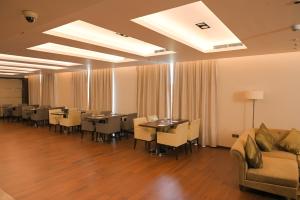 a dining room with tables and chairs and a couch at Courtyard by Marriott Kochi Airport in Nedumbassery