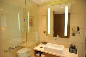 a bathroom with a sink and a toilet and a mirror at Courtyard by Marriott Kochi Airport in Nedumbassery