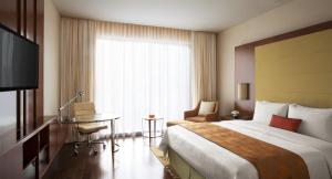 a hotel room with a bed and a desk and a window at Courtyard by Marriott Kochi Airport in Nedumbassery