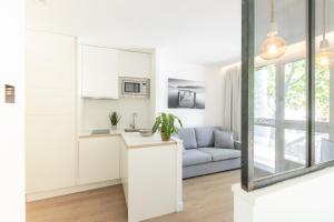 Les appartements de Montpellier في مونبلييه: مطبخ أبيض وغرفة معيشة مع أريكة