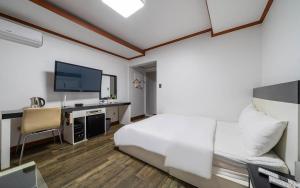 a bedroom with a bed and a desk with a television at Sokcho Time Hotel in Sokcho