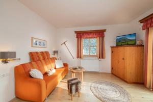 ein Wohnzimmer mit einem orangenen Sofa und einem Fenster in der Unterkunft Molteraugut in Mühlbach am Hochkönig