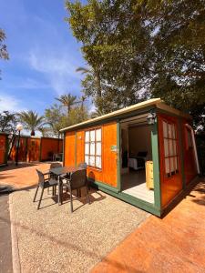 Camping Las Palmeras في كريفايلنت: منزل أخضر وبرتقالي مع طاولة وكراسي