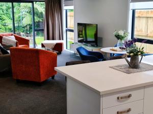 uma sala de estar com um sofá e cadeiras e uma televisão em Sunshine Haven - New 3-Bedroom 4-Beds in Paraparaumu em Paraparaumu