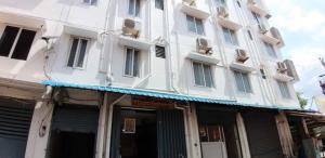un edificio blanco con un toldo azul delante de él en OYO Flagship Viswa Towers, en Madurai