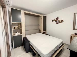 een kleine slaapkamer met een bed en een plank bij Charmant studio au cœur du centre-ville in Calvi