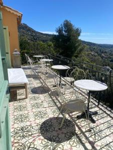 eine Gruppe von Tischen und Stühlen auf einem Balkon in der Unterkunft Villa with panoramic views near Grasse- 2175 in Spéracèdes