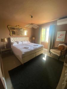 ein Schlafzimmer mit einem Bett, einem Spiegel und einem Stuhl in der Unterkunft Villa with panoramic views near Grasse- 2175 in Spéracèdes