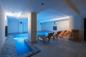ein Raum mit einem Pool, Stühlen und einem Tisch in der Unterkunft GANZ Hotel & Spa in Iwano-Frankiwsk