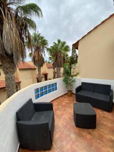 a patio with two black couches and palm trees at El Olivar Paraíso Playa in Parque Holandes