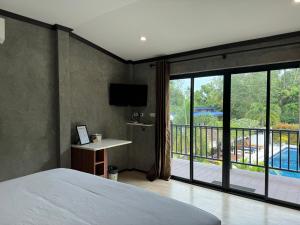 1 dormitorio con 1 cama y balcón con TV en BAAN CHAINARONG en Ko Lanta