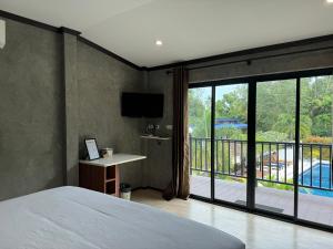 1 dormitorio con 1 cama y balcón con TV en BAAN CHAINARONG, en Ko Lanta