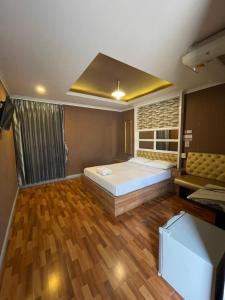 een slaapkamer met een bed en een bank erin bij โรงแรมกู๊ดอินน์ in Phra Nakhon Si Ayutthaya
