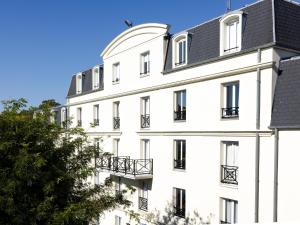 un bâtiment blanc avec un toit noir dans l'établissement Hôtel Baudouin, à Valenciennes