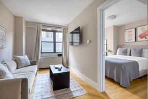 - une chambre avec un lit, un canapé et un miroir dans l'établissement UES 1br w gym doorman walk to central park NYC-1332, à New York