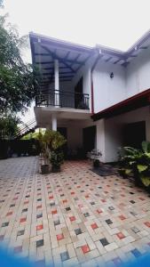 un edificio con balcón y patio de azulejos en Sensitha Holiday home, en Anuradhapura