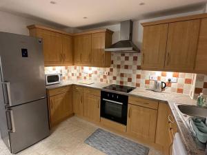a kitchen with wooden cabinets and a stainless steel refrigerator at 2 Bedrooms Luxurious Apartment in Luton in Luton