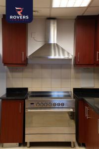 cocina con fogones de acero inoxidable horno superior en Rovers Hostel Dubai en Dubái