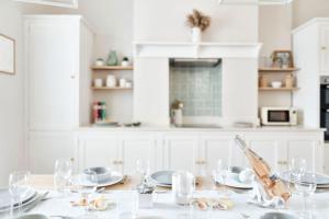 uma cozinha branca com uma mesa com pratos e copos em Cute Beach House - 4 mins walk em Bournemouth