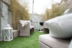 a small backyard with grass and wicker chairs at Cute Beach House - 4 mins walk in Bournemouth