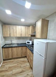 cocina con armarios de madera y nevera blanca en Apartment Svetlana 7 en Alicante