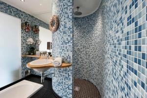 a bathroom with blue tiles and a sink and a tub at Quirky and Modern Clerkenwell Apartment in London