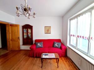 a red couch in a living room with a table at Appartamento Pelmo in Borca di Cadore