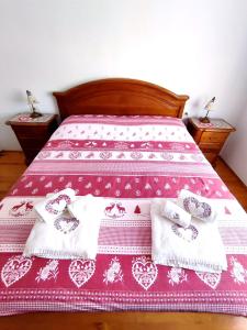 a bed with a pink and white bedspread and towels at Appartamento Pelmo in Borca di Cadore