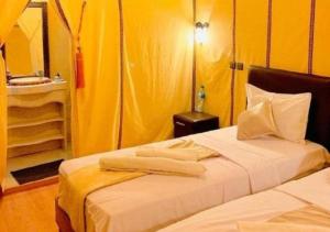 two beds in a room with yellow walls at Fantastic Desert Luxury Camp in Merzouga